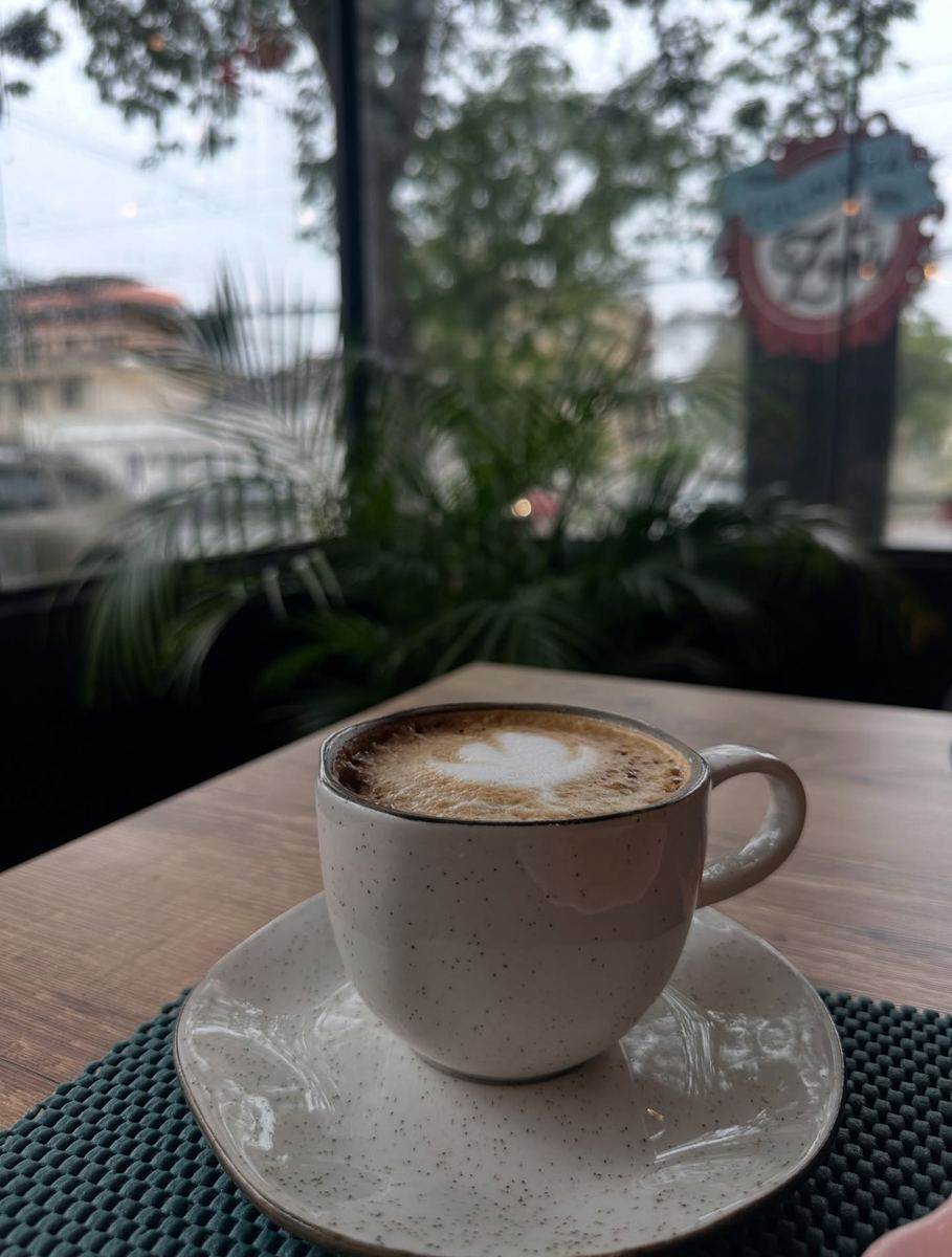 Café servido à mesa da Culinária da Zeni, com a fachada da loja ao fundo